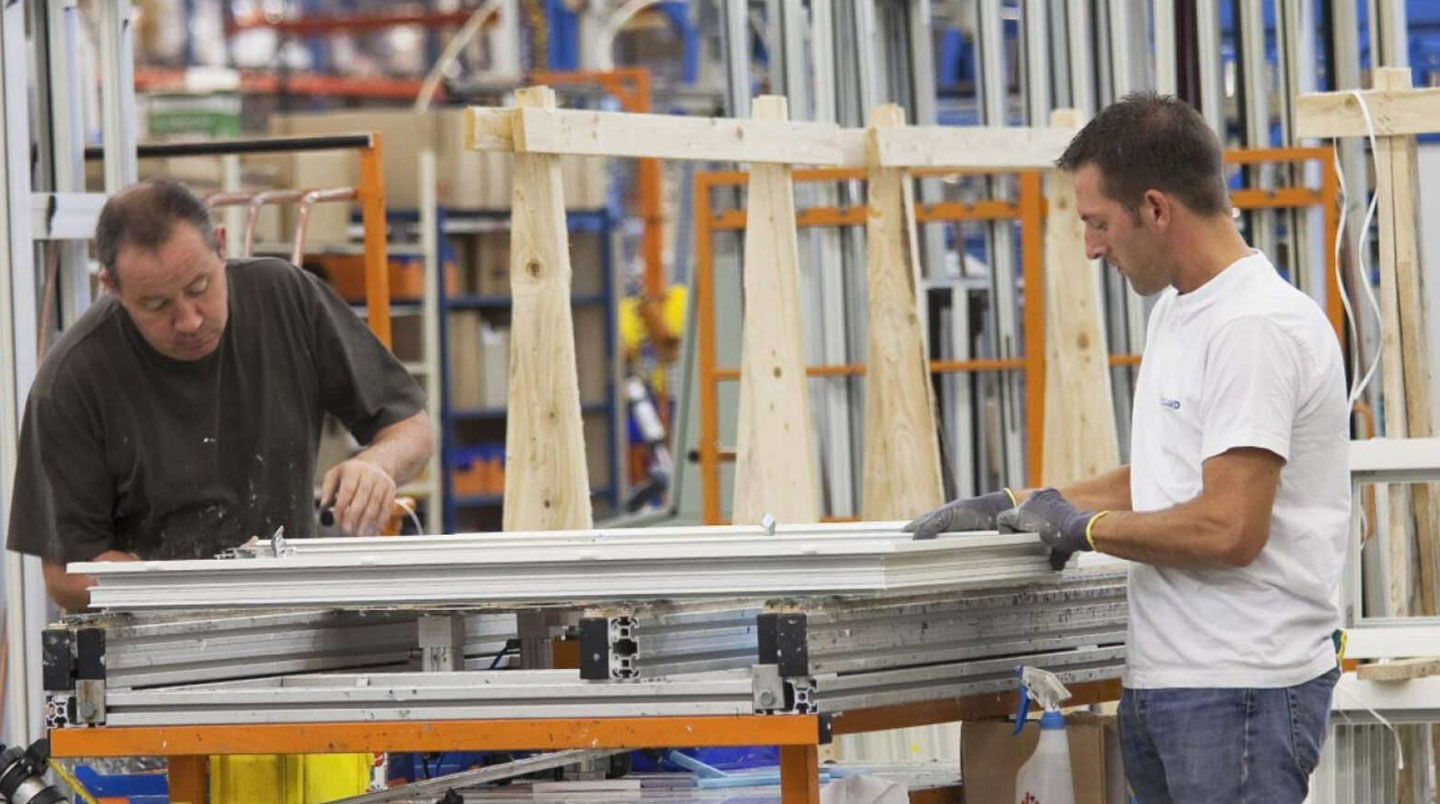 Atelier de fabrication de menuiseries avec machine CNC découpant des profilés PVC selon mesures personnalisées
