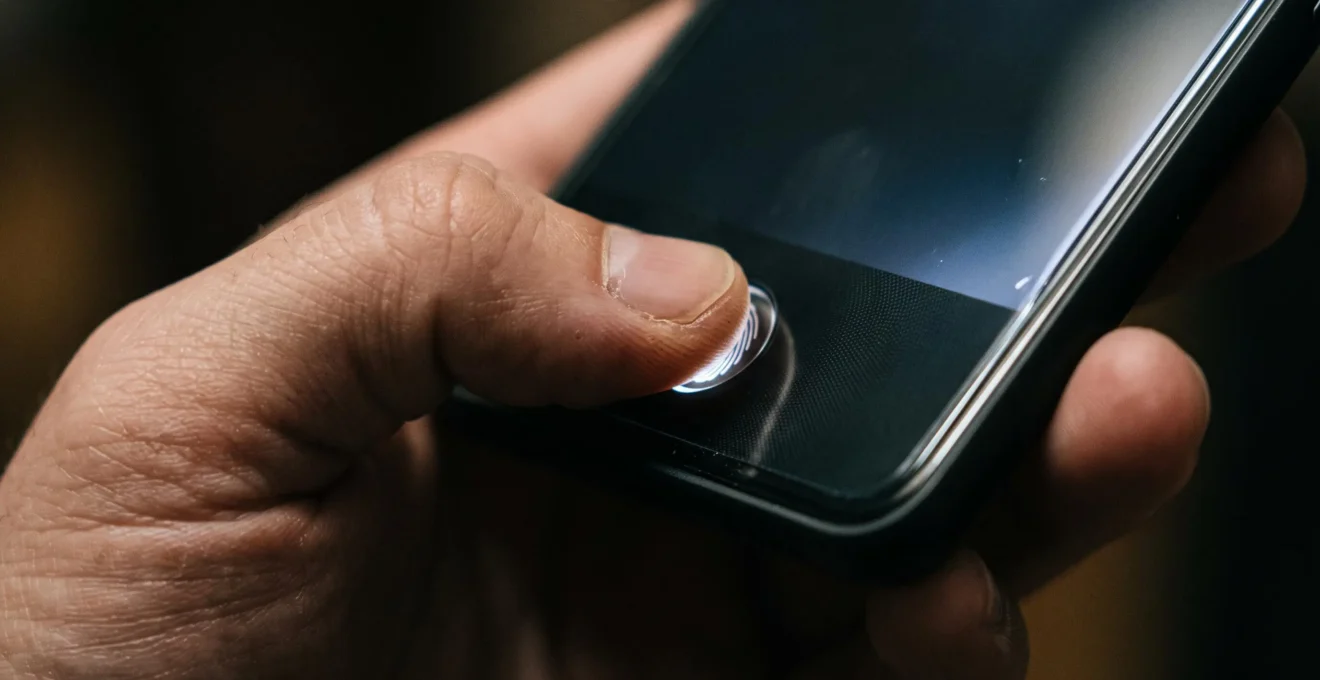 Gros plan sur un pouce effectuant une authentification biométrique par empreinte digitale sur un smartphone